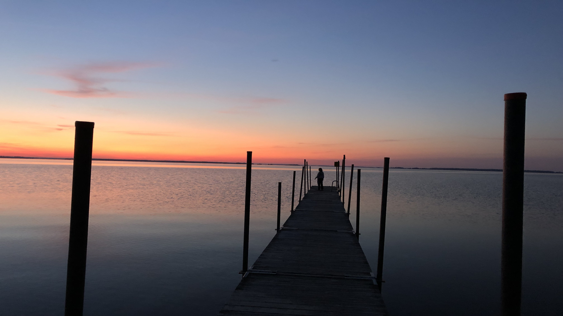 Auf einem einsamen Steg n einem See in Schweden mit Blick in den roten Sonnenuntergang.