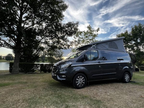 Wohnmobil Nugget Plus von Ford steht in Frankreich in einem Schlosspark an einem See.